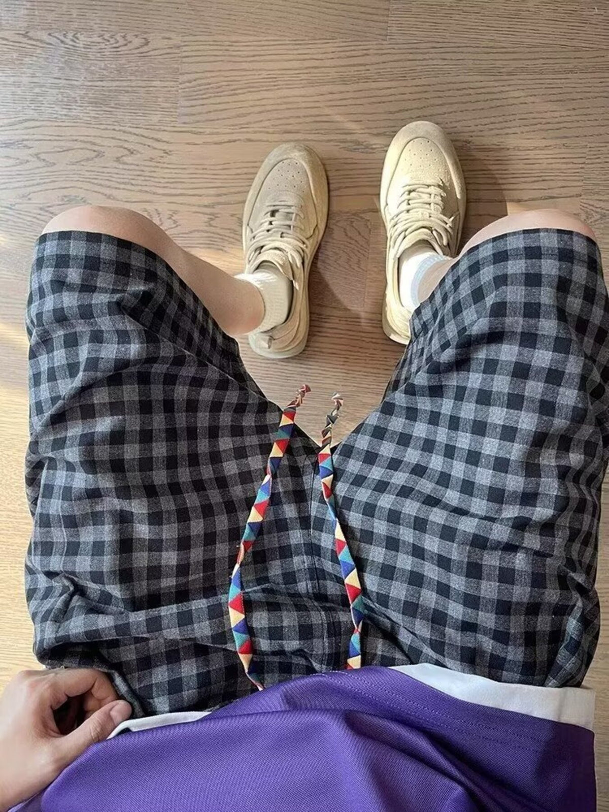 Plaid drawstring shorts laid flat with multicolor tie strings and dark gray check pattern