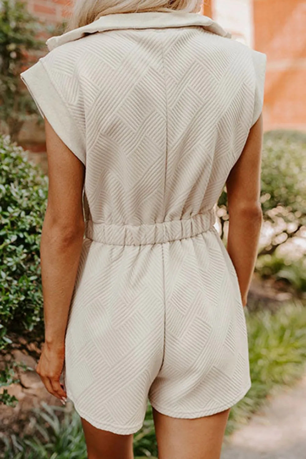 Cream textured zip-front romper, back view with sleeveless cut and short legs