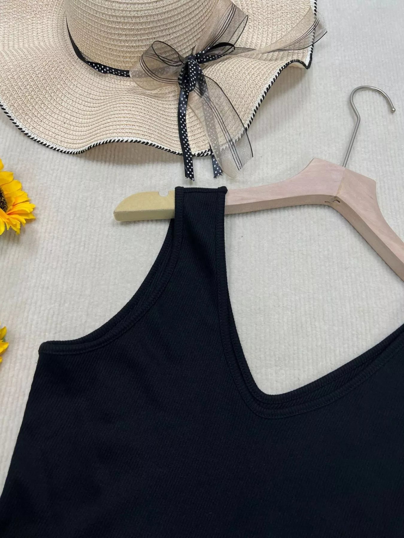 Cedar & Moore V-Neck Slim Fit Tank in black, displayed on a wooden hanger beside one beige sun hat.