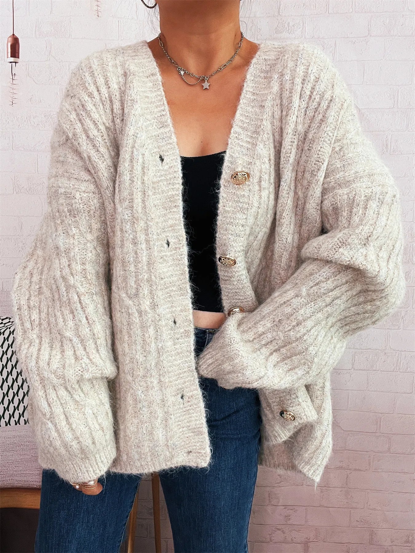 Cream cable knit cardigan featuring V-neck, long sleeves, and gold-tone buttons
