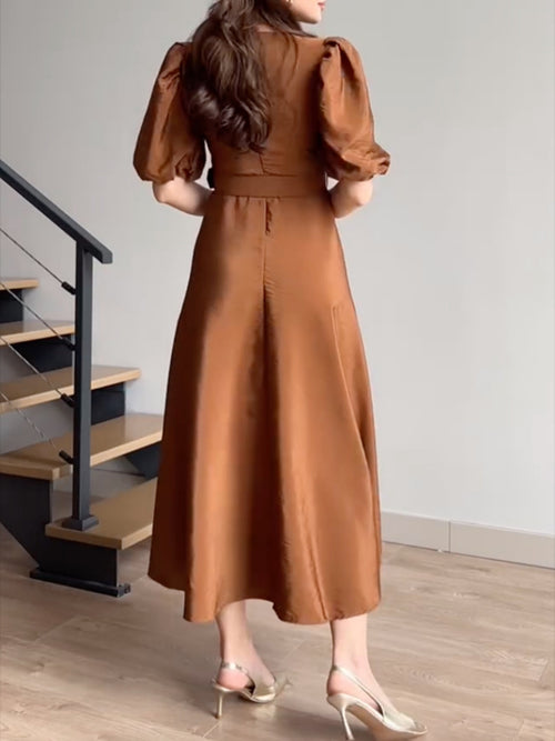 Tan belted midi dress with puff sleeves, fitted bodice and flared skirt