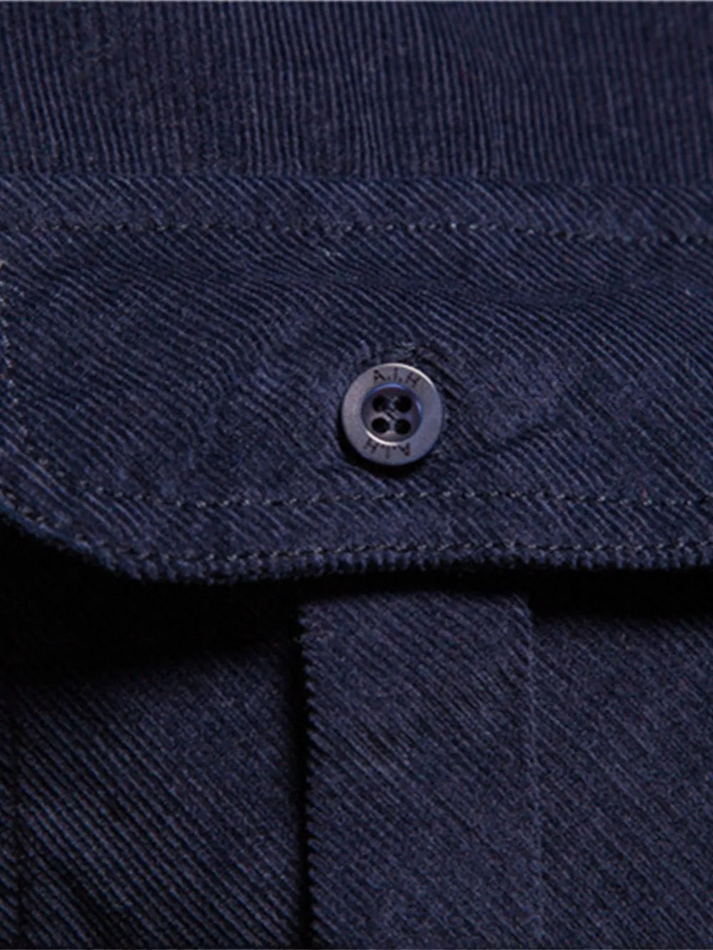 Men's dark indigo button-down shirt collar detail with round button and textured fabric