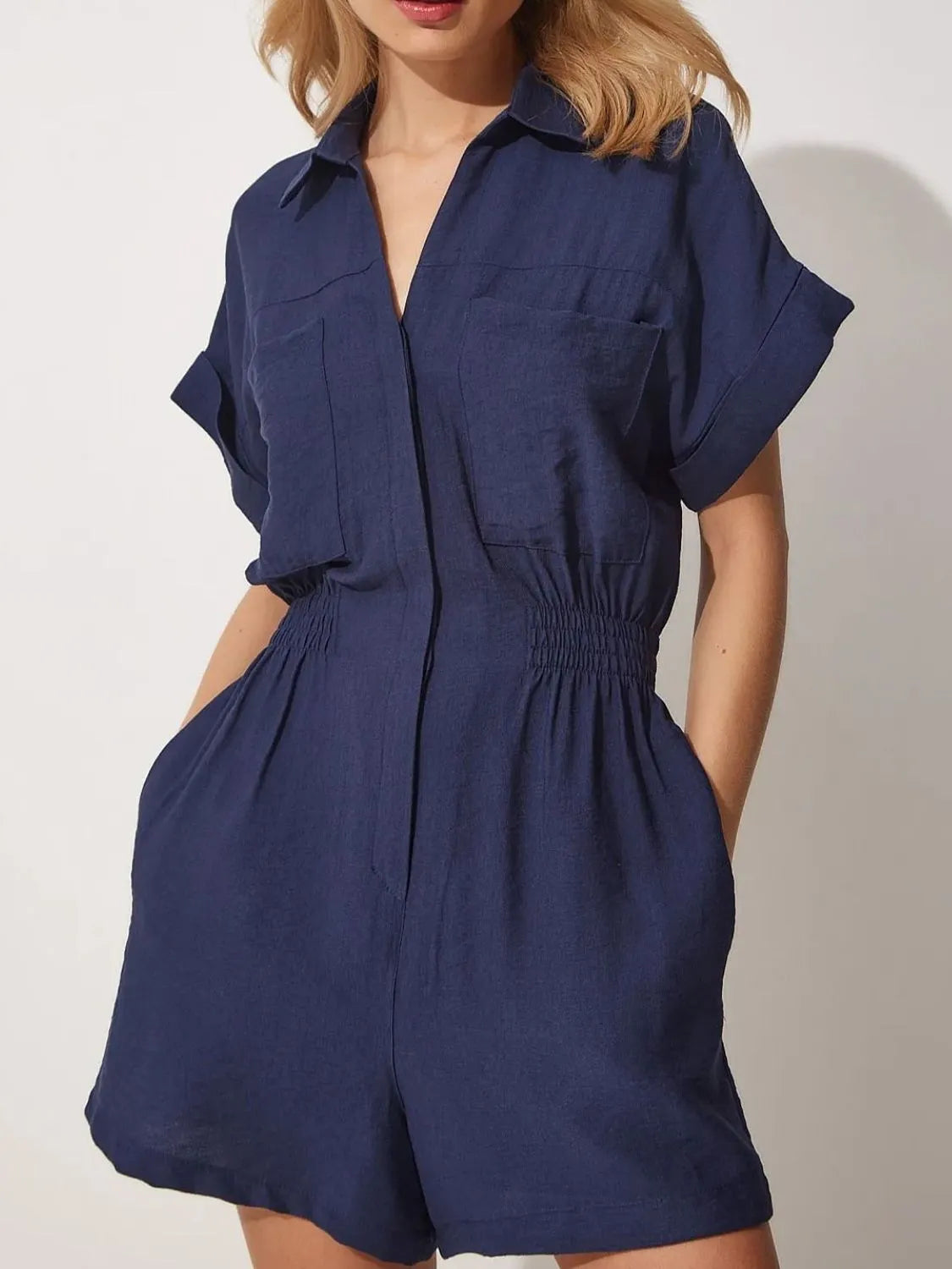Dark blue short-sleeve romper with collar, button front, patch pockets, and elastic waist.