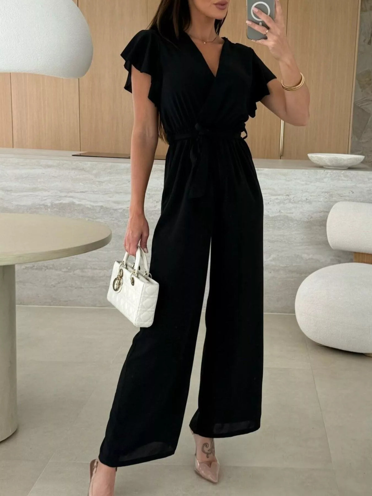 Black surplice wide-leg jumpsuit with ruffle sleeves and ruched tie waist