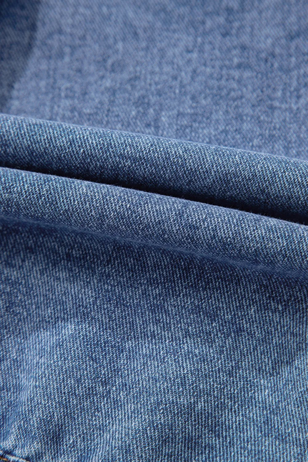 Denim jacket fabric close-up with woven texture and seam stitching