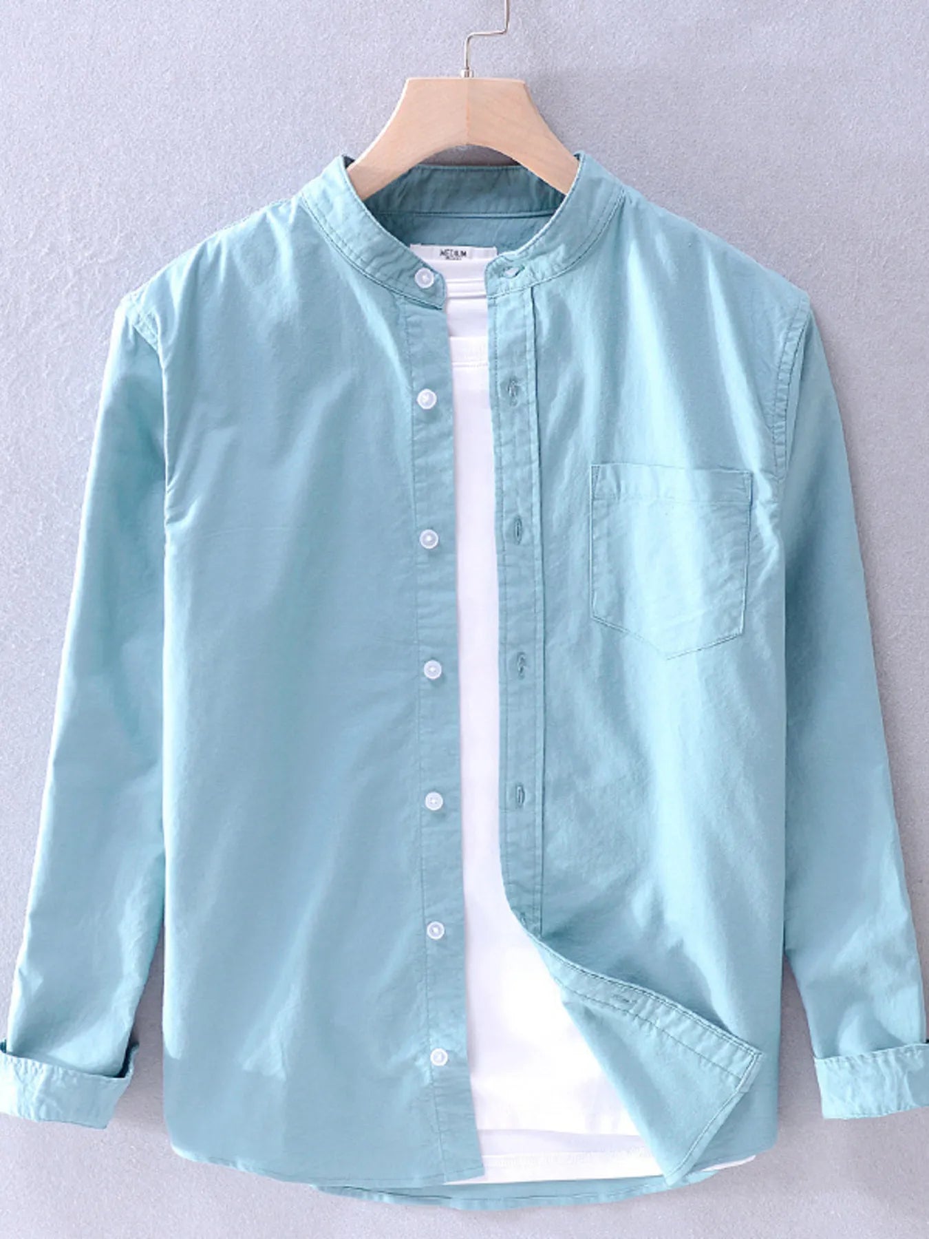 Long-sleeve button-up shirt in light teal with front buttons and chest pocket