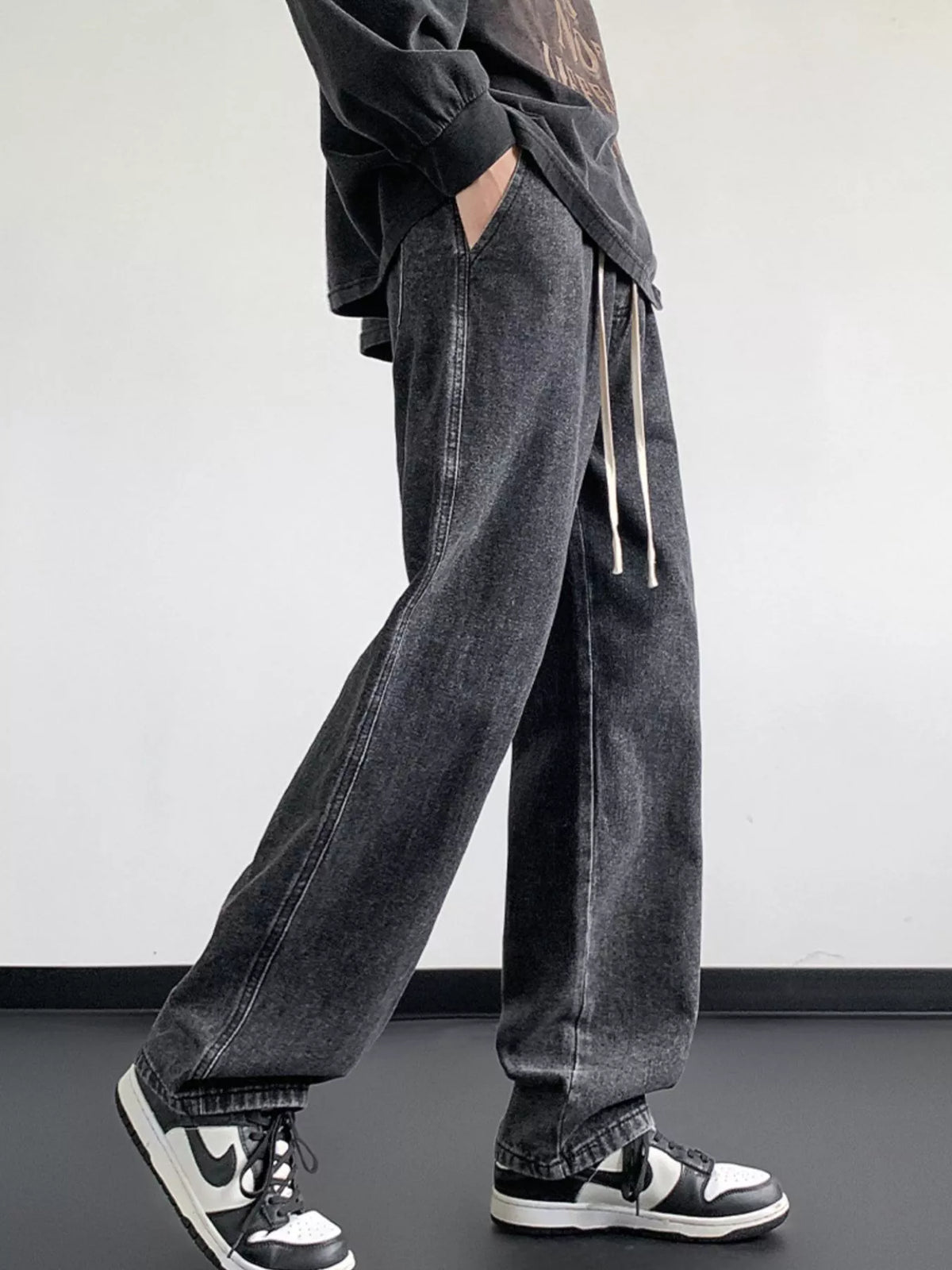 Dark gray washed denim jeans with relaxed fit, wide legs, and drawstring waistband