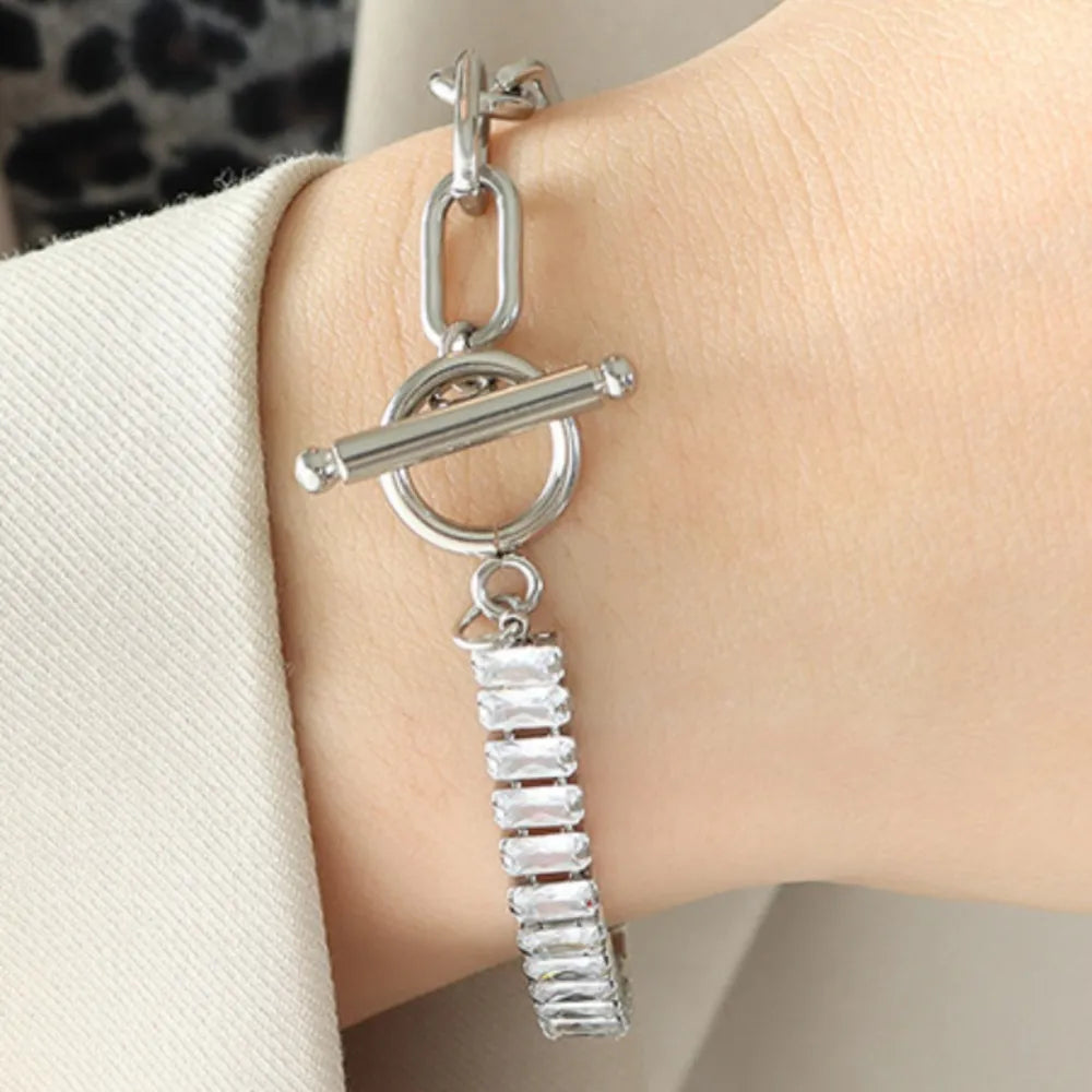Silver-tone closure bracelet with bar charm, oval ring link, and rhinestone row