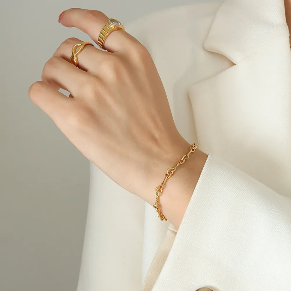 Gold link chain bracelet on wrist with small oval tag and toggle clasp