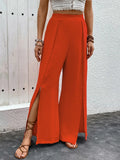 Orange-red high-waist wide-leg slit pants with draped, textured fabric