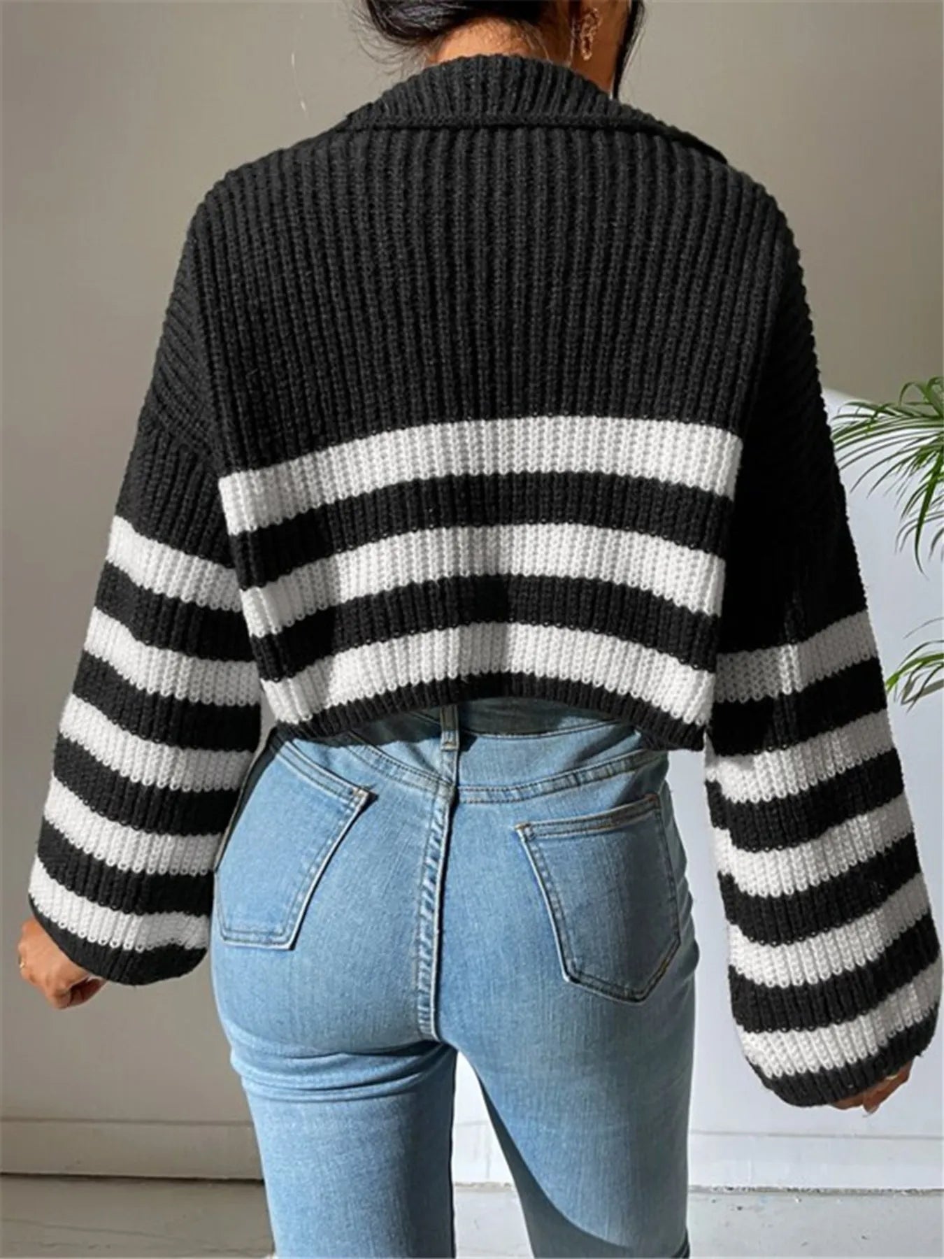 Back view of black ribbed cropped half-zip sweater with white-and-black striped banding