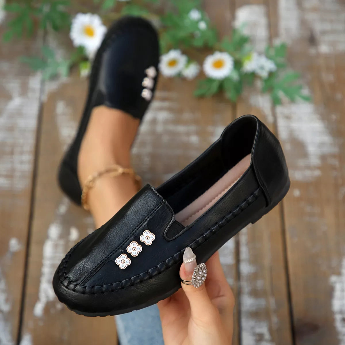 Black round-toe slip-on flats with floral charms on the front vamp