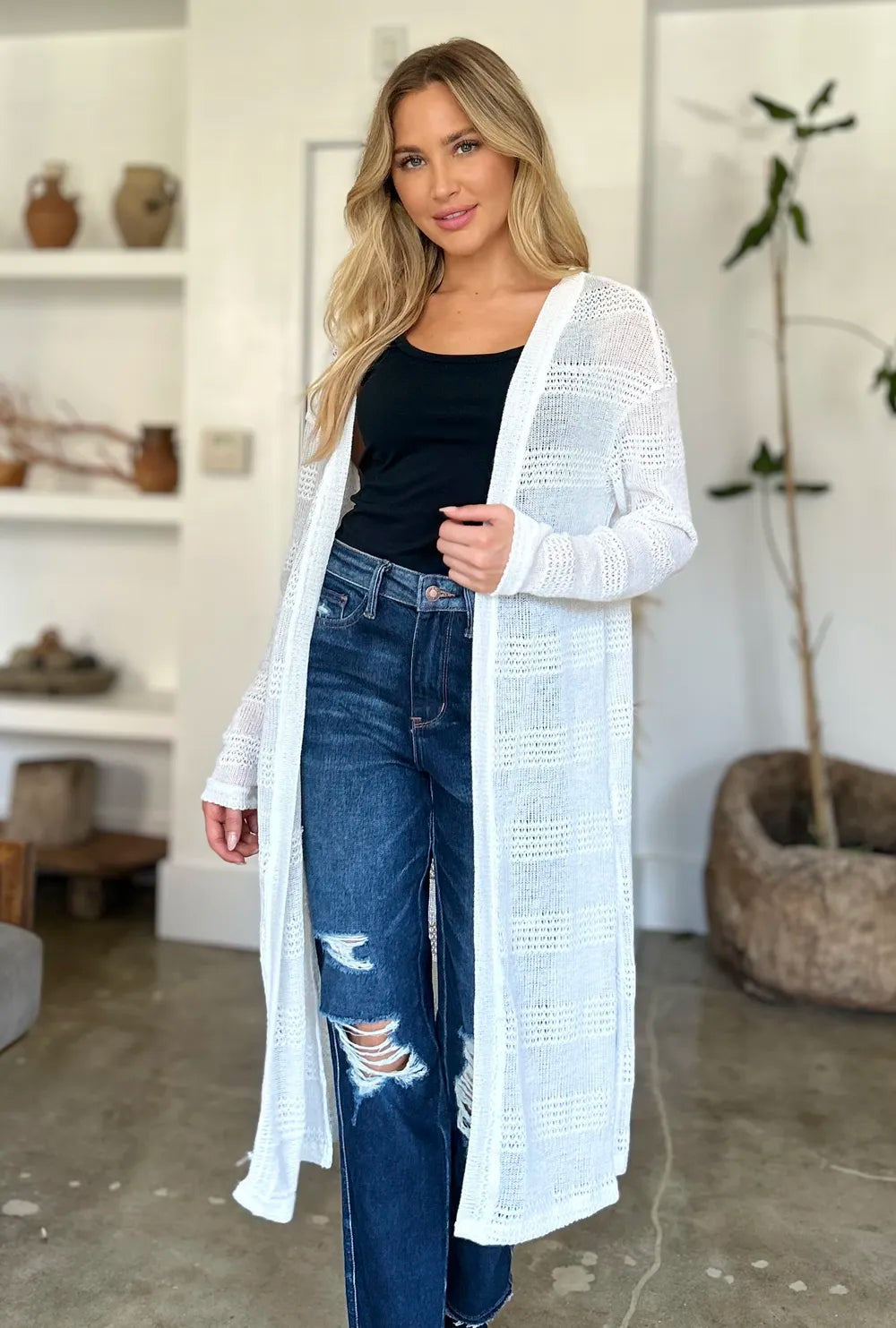 Longline open-front striped knit cardigan with long sleeves, worn over jeans and a top.