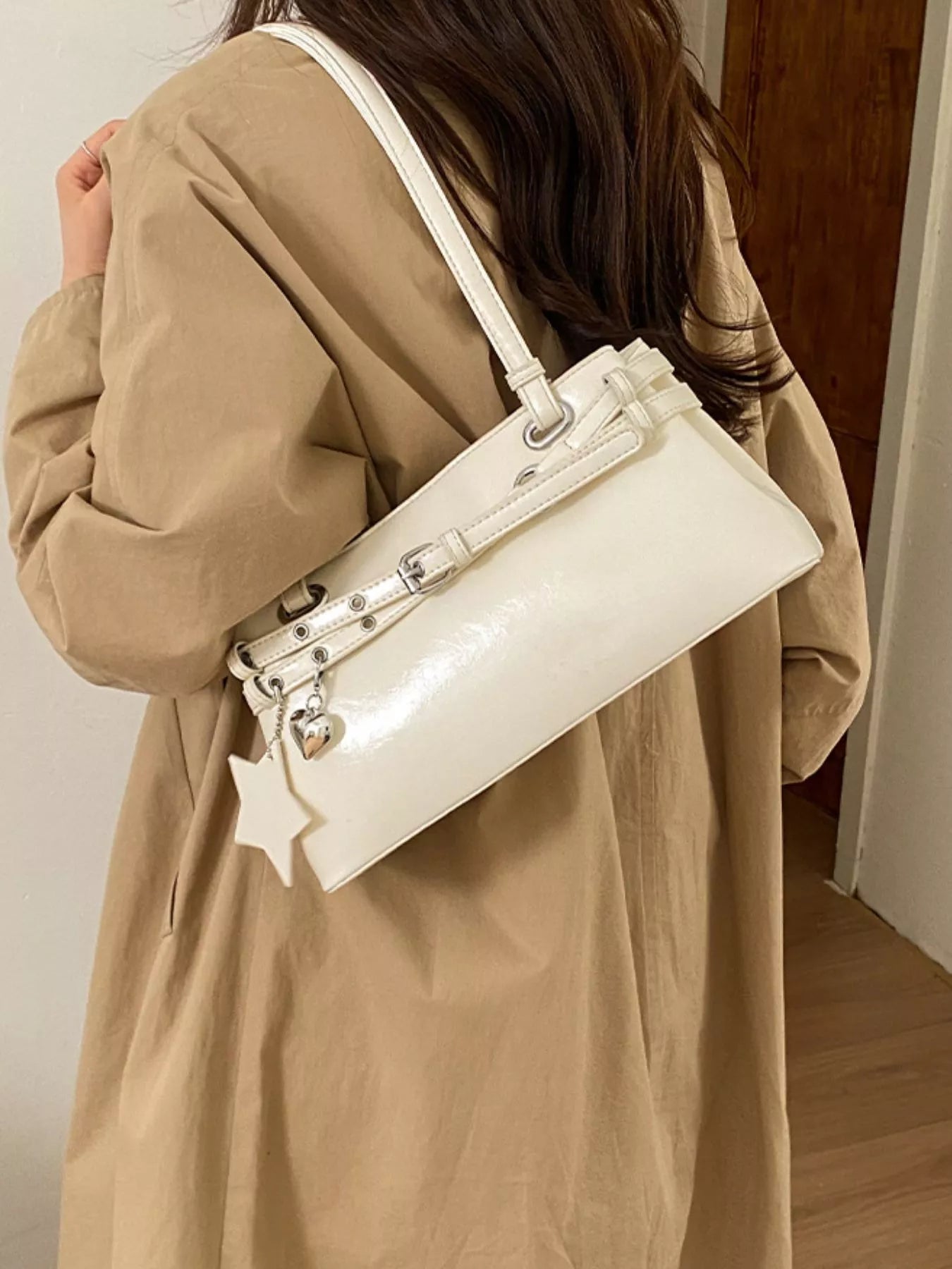 White vegan leather shoulder bag with star buckle detail, angled side view, structured shape