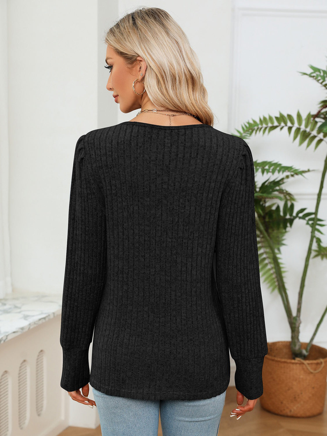 Black ribbed knit blouse, back view with long sleeves and curved hem