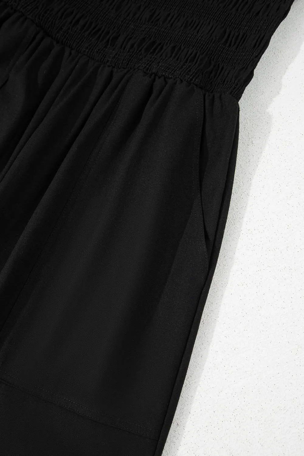 Black smocked spaghetti-strap jumpsuit with gathered waist