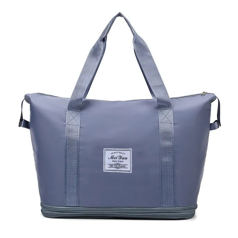 Dusty blue large duffle bag with two top handles, side straps, and front logo patch