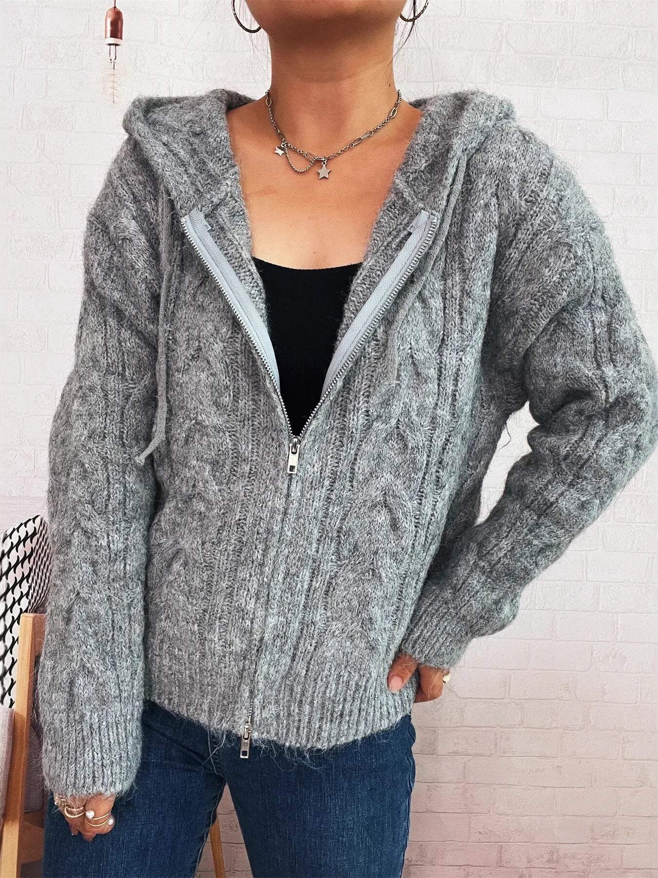 Gray hooded cable knit zip-up cardigan with front zipper and long sleeves, ribbed cuffs.
