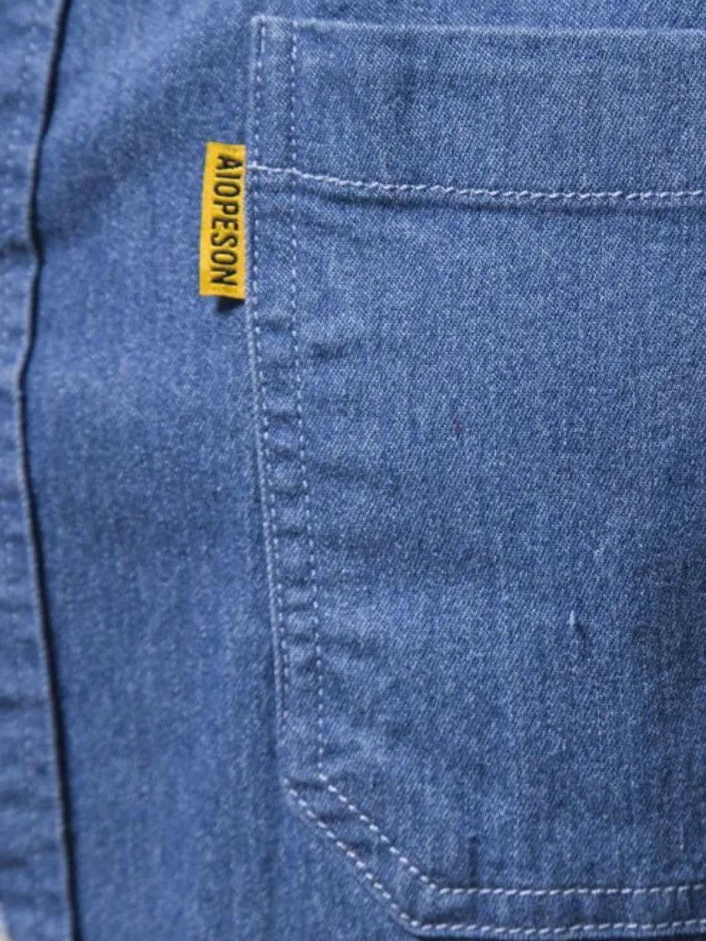 Denim button-up shirt closeup with stitched placket and yellow tag