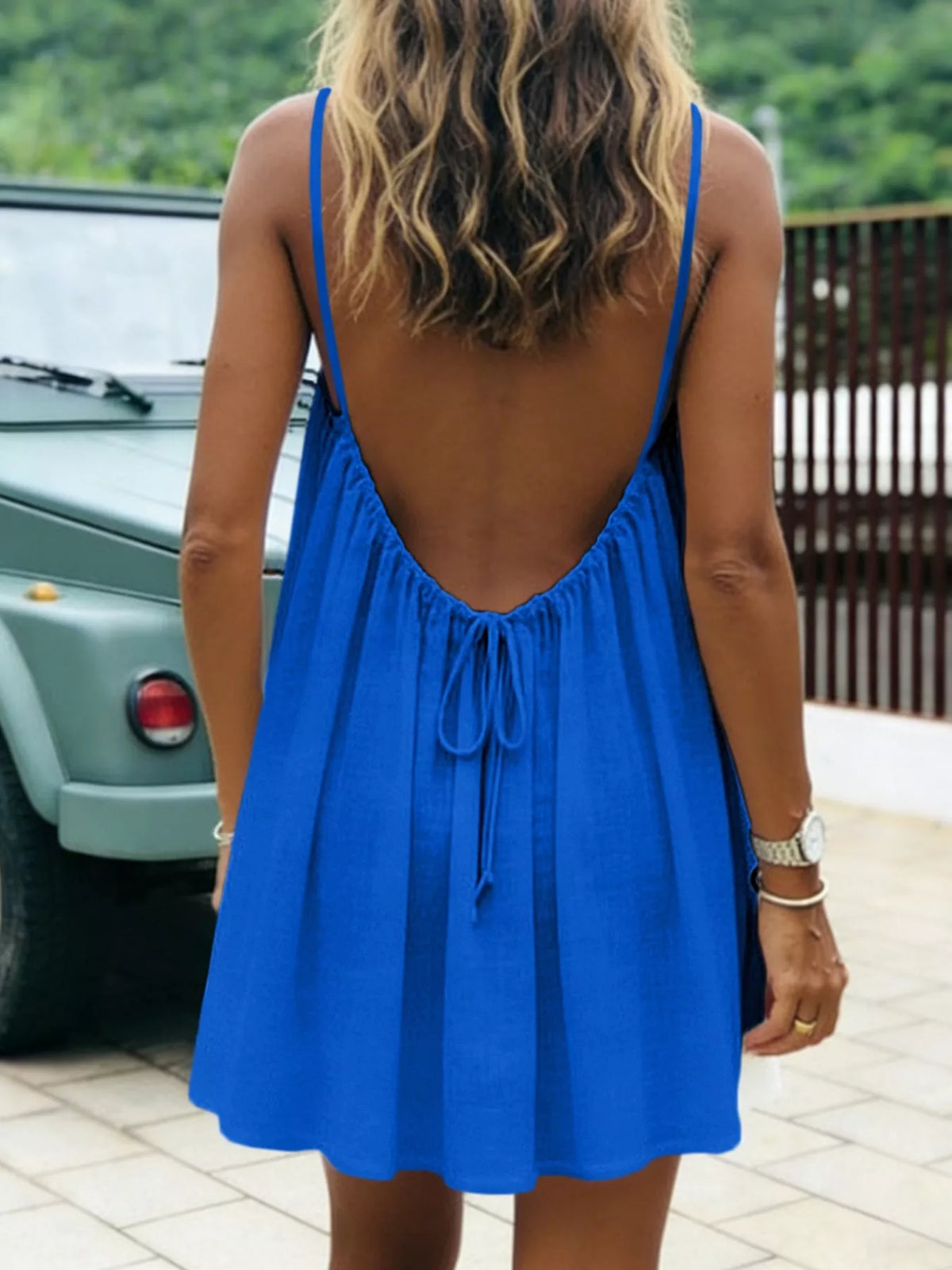 Back view of royal blue ruched spaghetti strap mini dress with tie at neckline