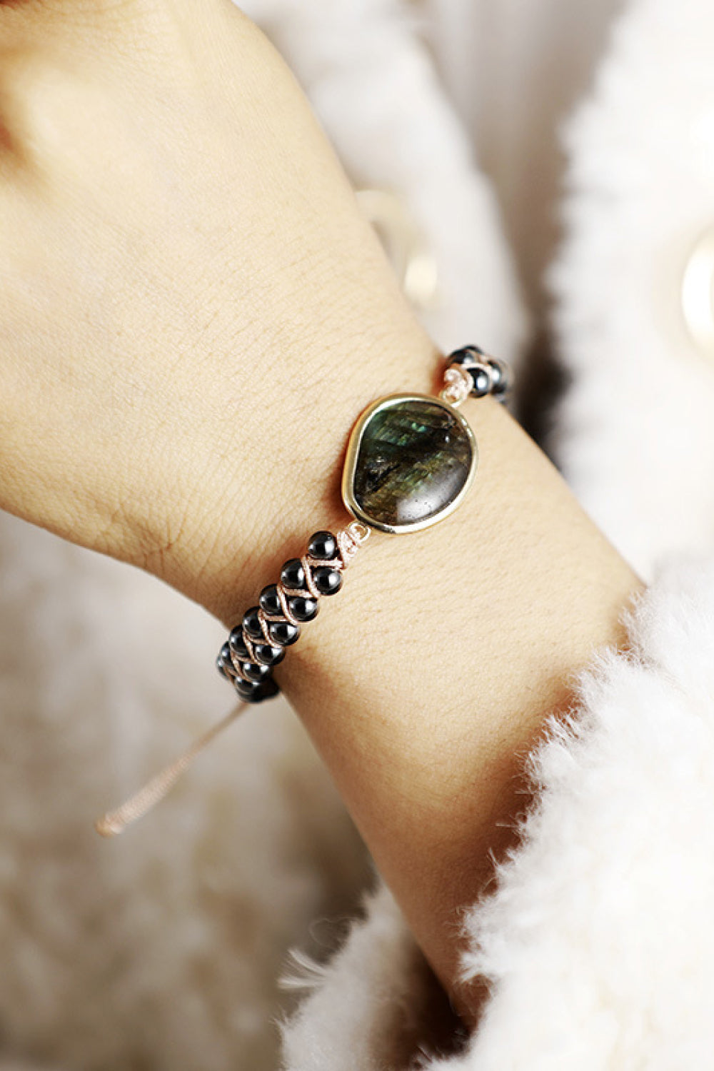 Black beaded bracelet on wrist with round labradorite stone and gold-tone bezel
