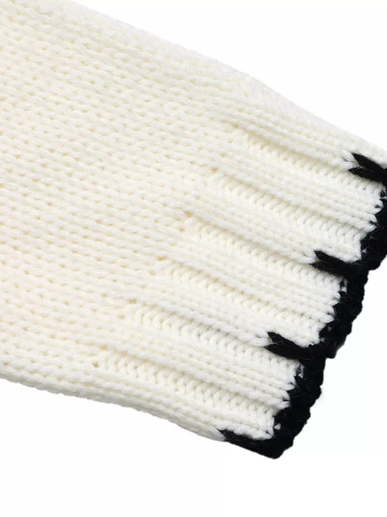 Ivory sweater sleeve cuff with black stripe detail and ribbed knit texture