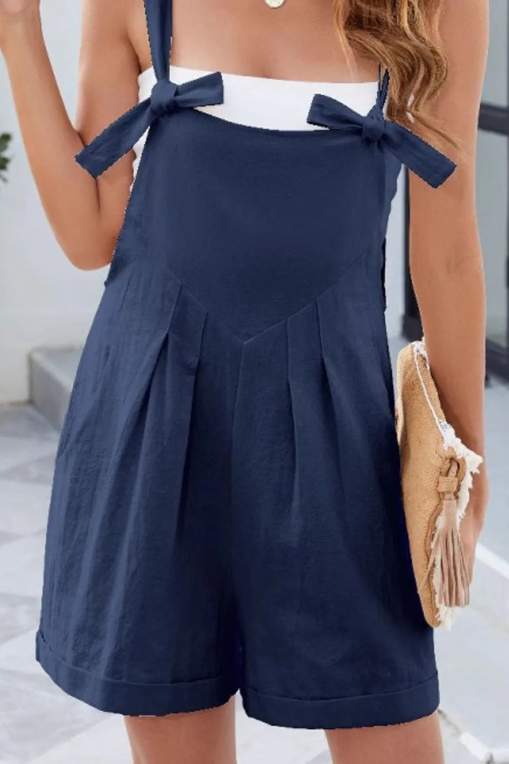 Dark navy knotted-strap romper with side pockets and bow detail at chest