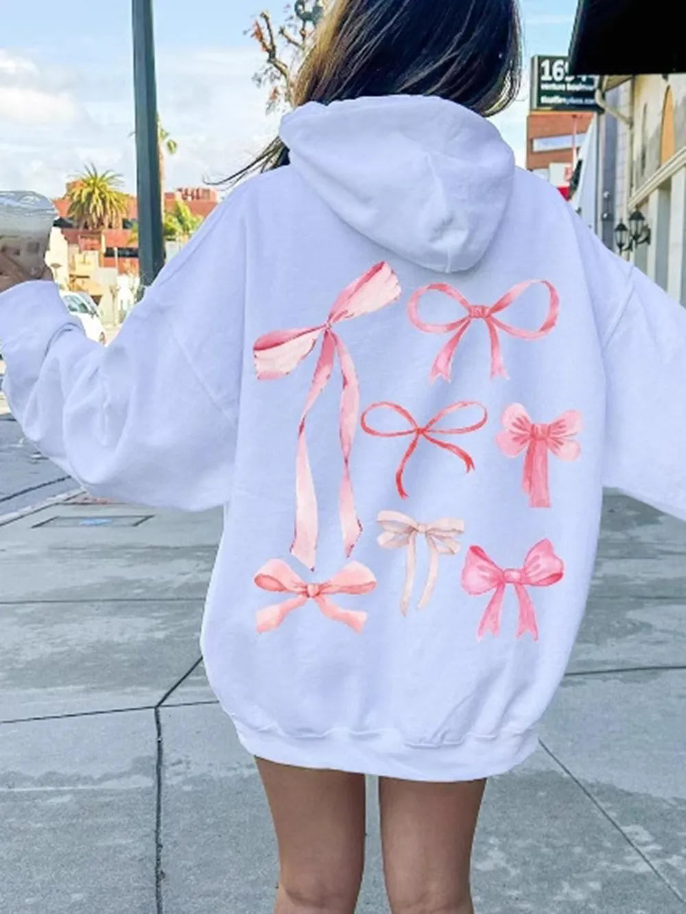 White long-sleeve hoodie with large pink bow graphic on the back
