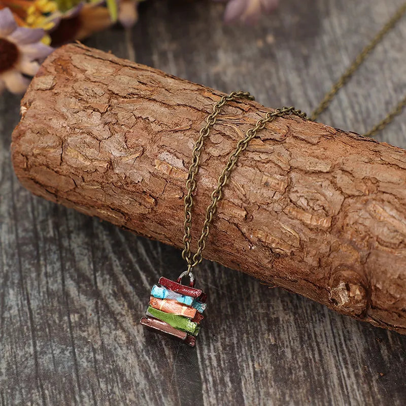 Gold-tone pendant necklace with stacked multicolor book-shaped charm on cork