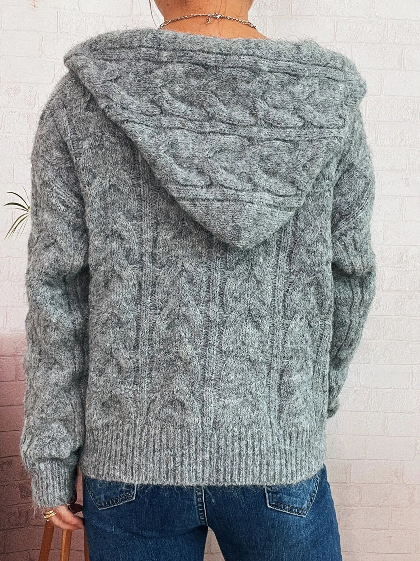 Gray cable knit hooded zip-up cardigan, view of back with hood and textured knit pattern.