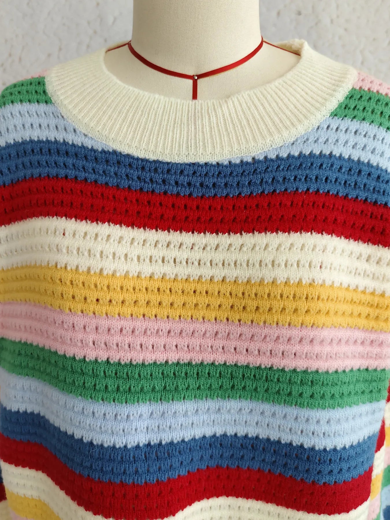 Rainbow striped sweater neckline in cream knit with red trim