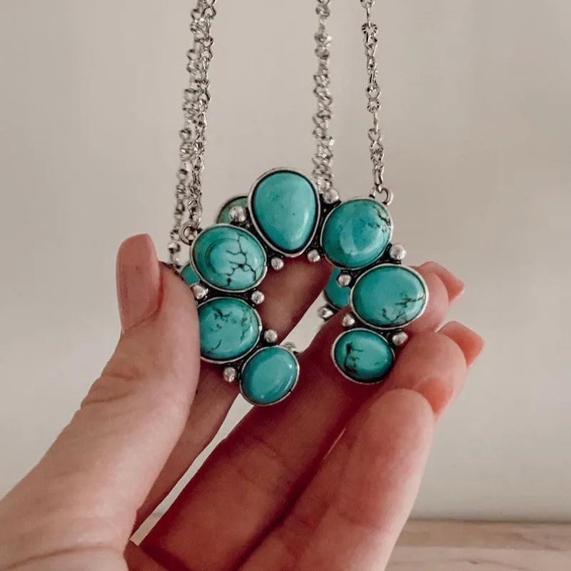 Turquoise oval stone pendant necklace held in hands, silver-tone chain visible.