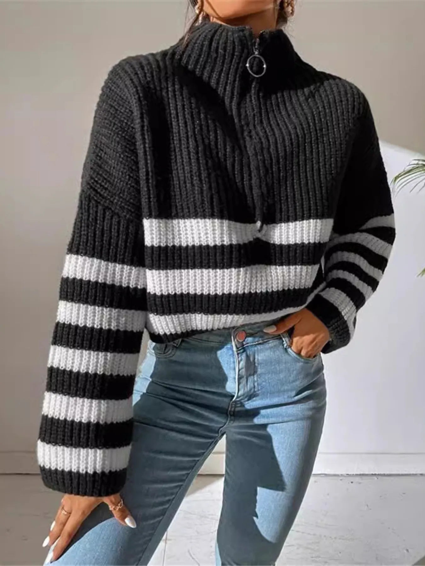 Black cropped ribbed sweater with half-zip front and wide white stripe across chest