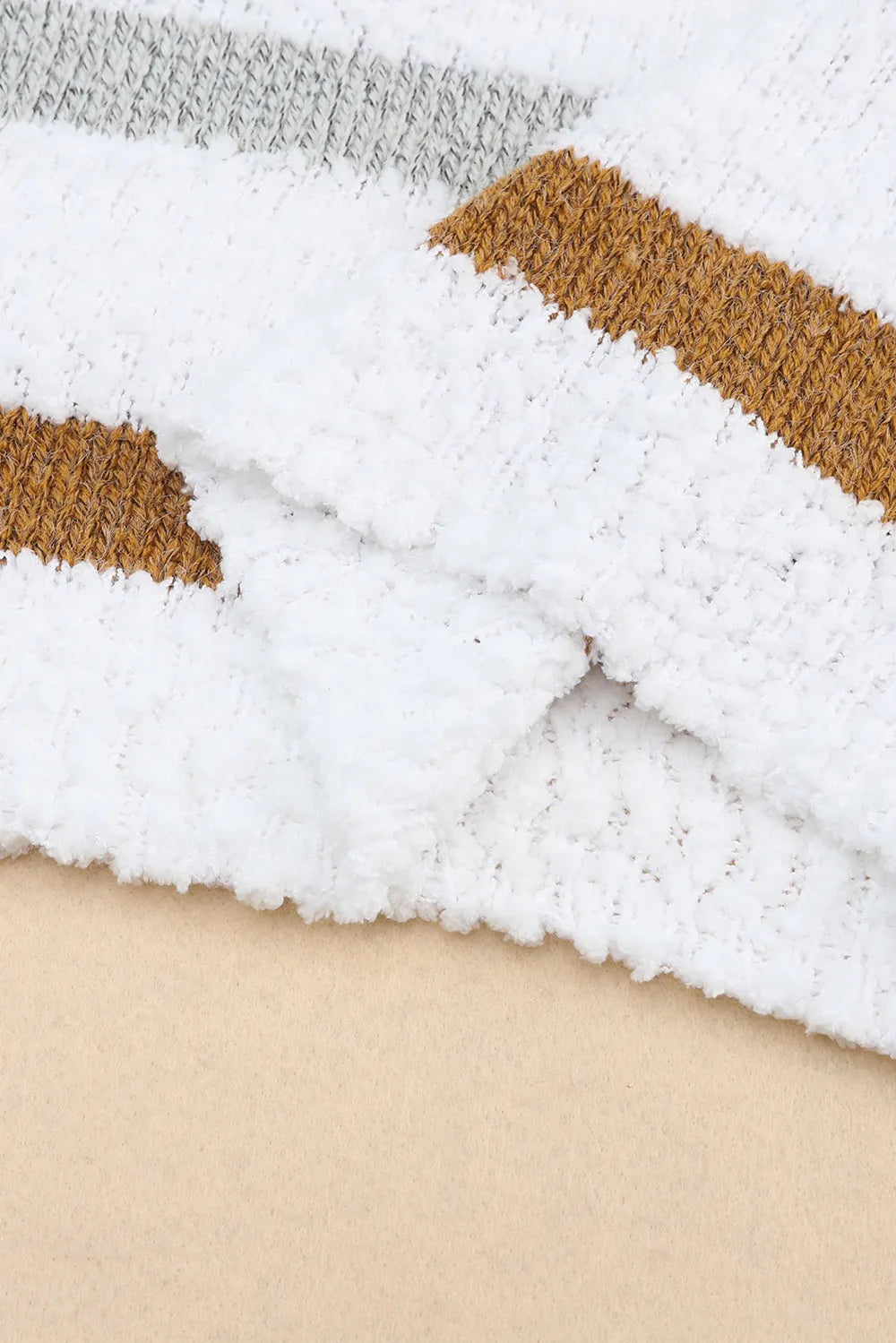 White knit sweater hem with tan and black horizontal stripe bands