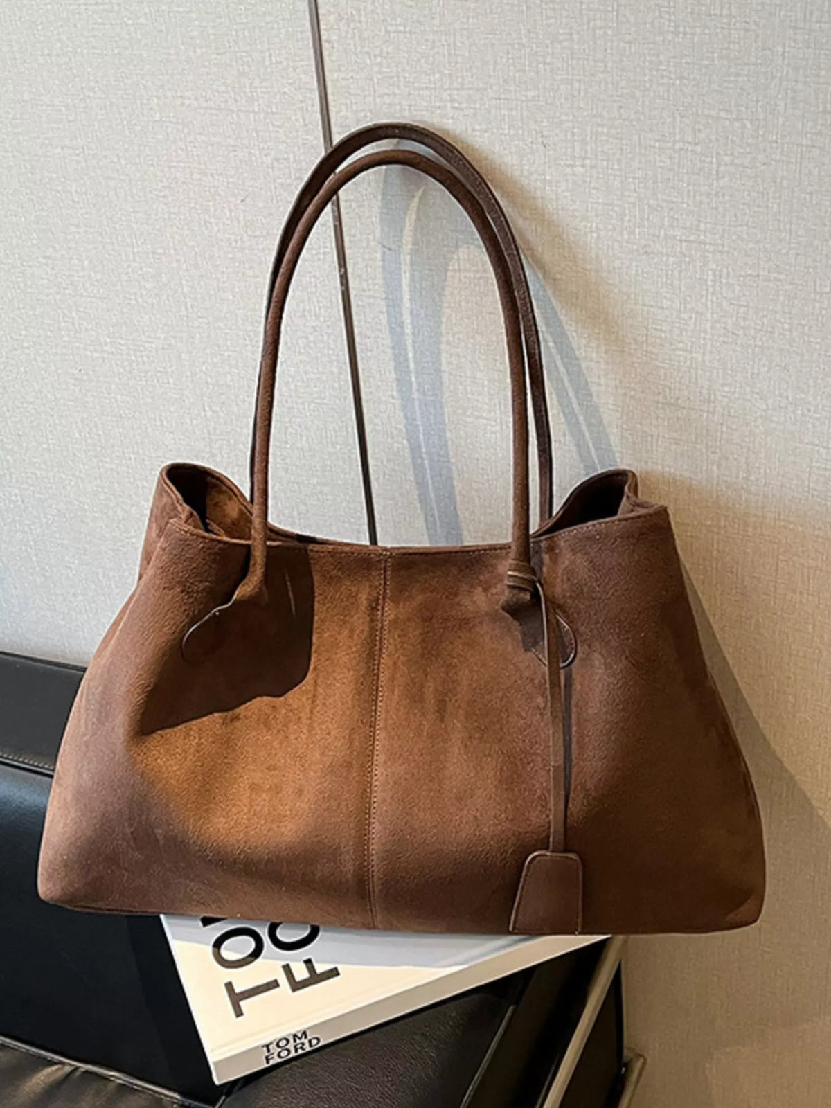 Brown suede tote bag with tall handles, side tabs, and front strap pocket