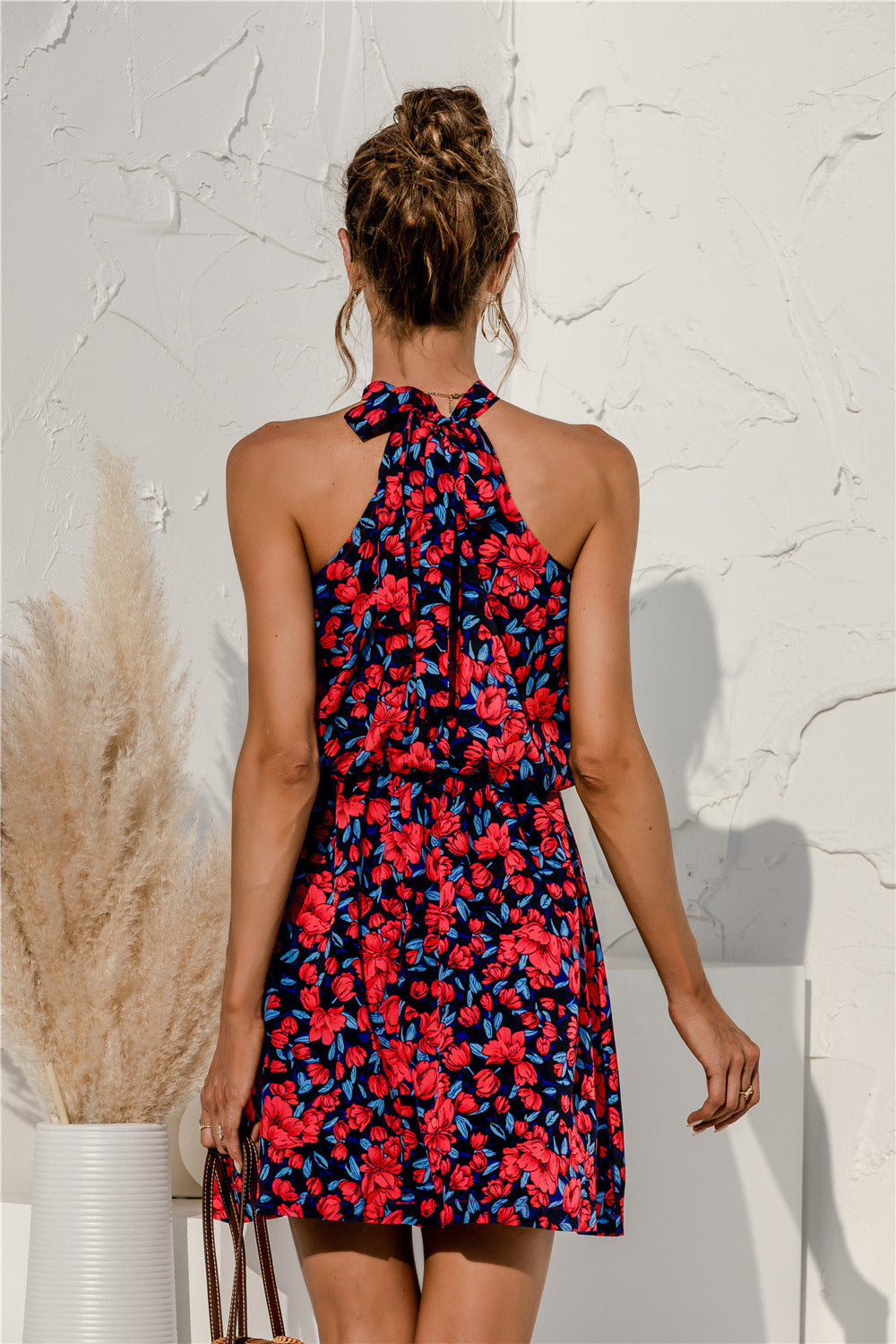 Back view of red floral sleeveless mini dress with halter tie straps