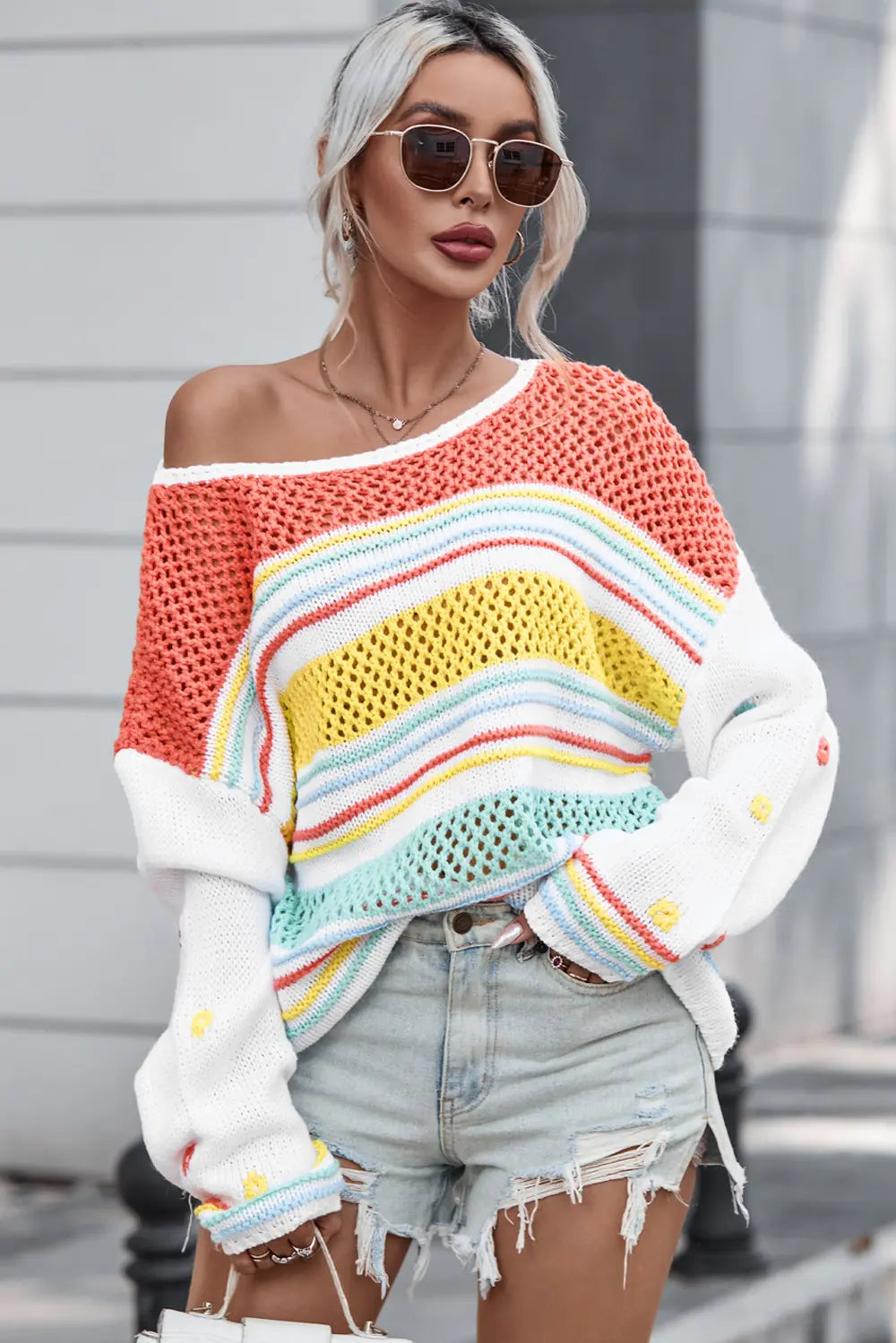 Openwork striped sweater, front view; orange knit with rainbow stripe band and long white sleeves