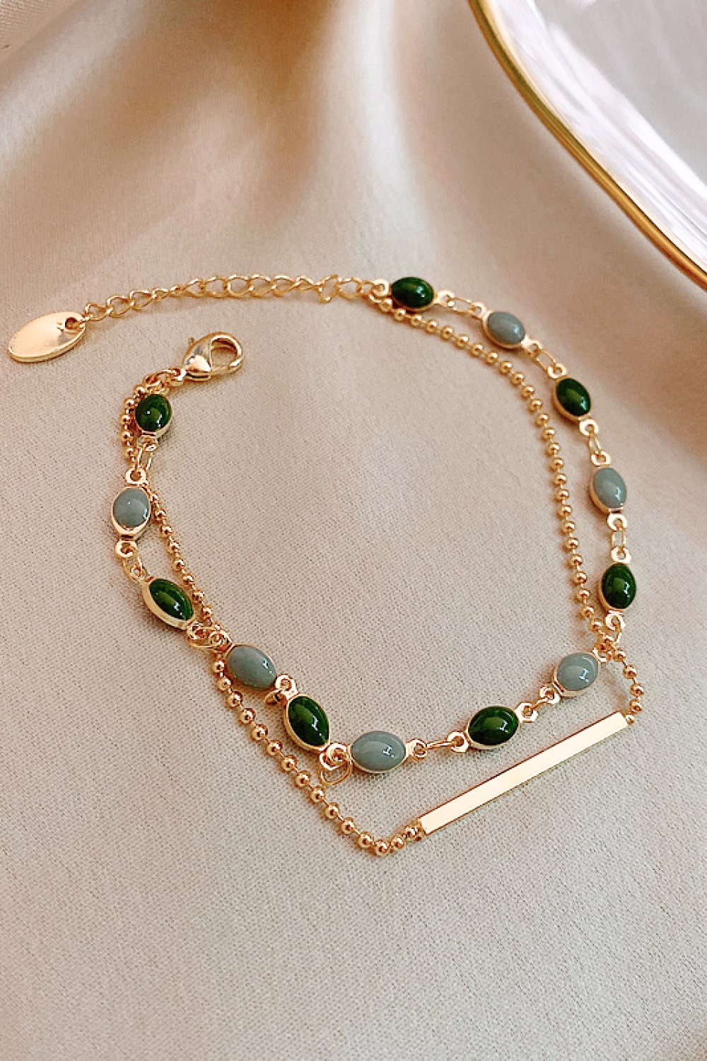 Gold-tone double-layer bracelet with green and gray beads and flat bar charm