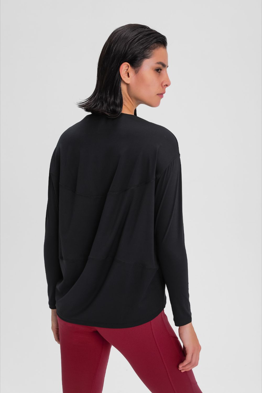 Loose fit active top in black, back view with long sleeves and loose drape.