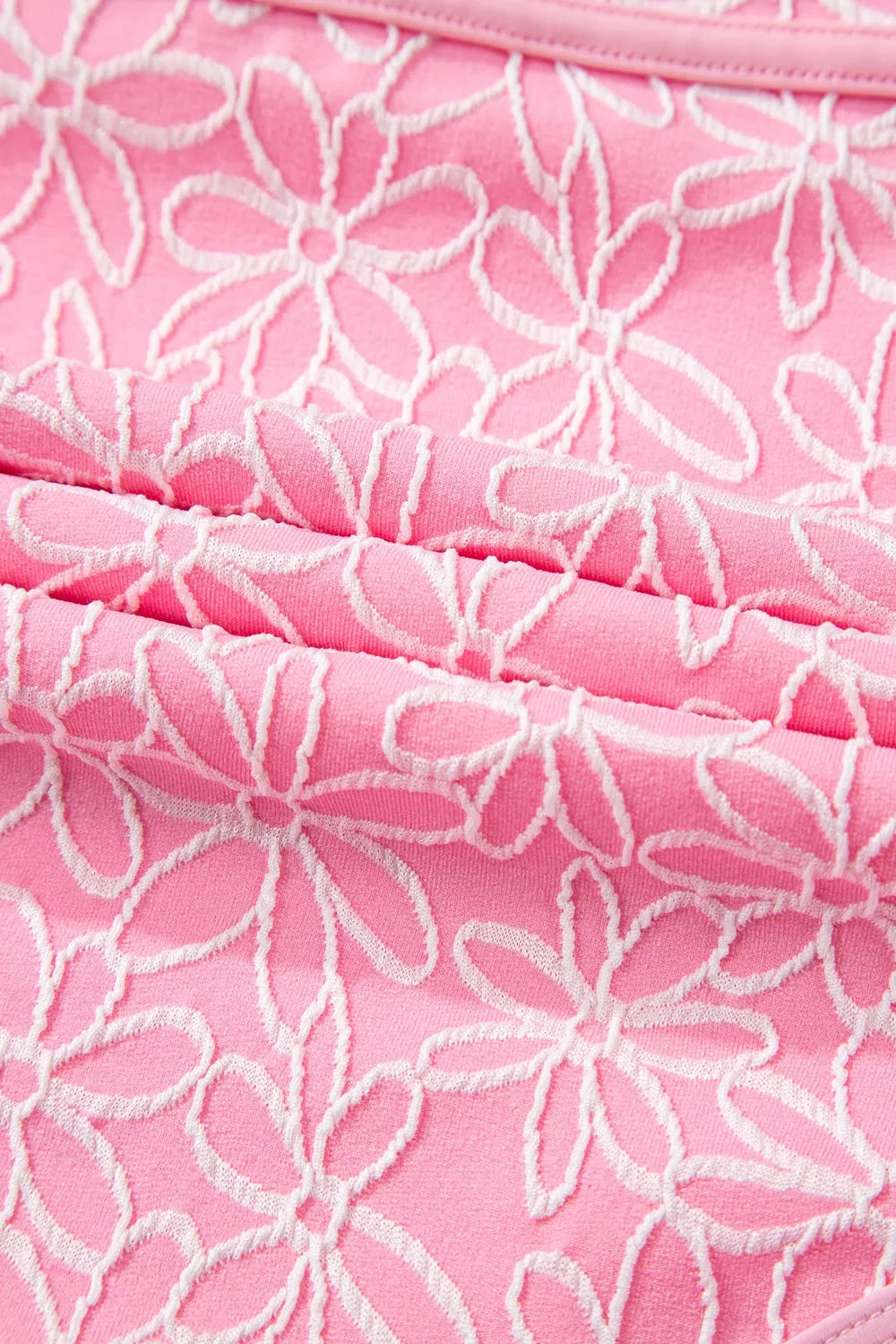 Blush pink floral textured one-piece swimsuit fabric close-up with white daisy pattern