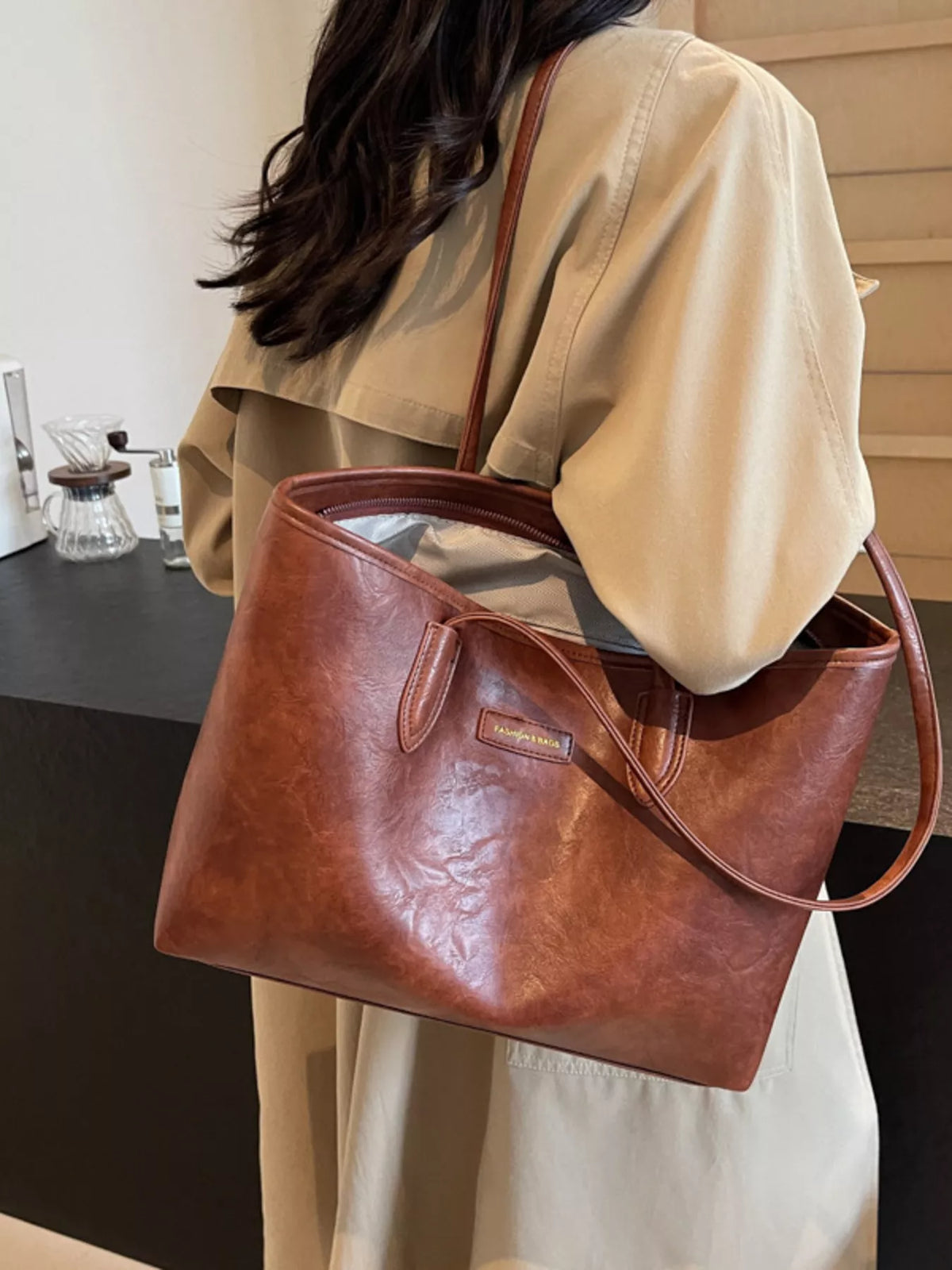 Brown vegan leather tote bag with curved top handles and front pocket panel