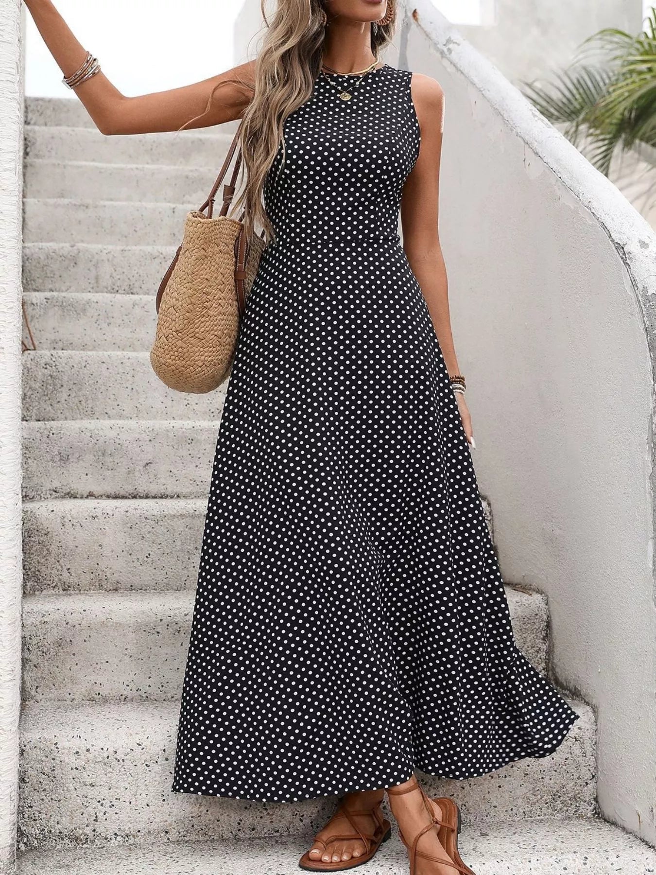 Cedar & Moore Sleeveless Polka Dot Maxi Dress in black with white dots, with straw tote and sandals, by Trendsi