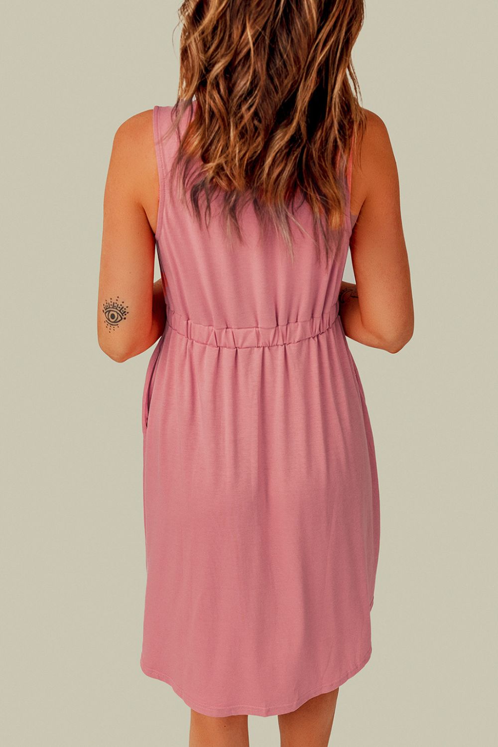 Back view of pink sleeveless mini dress with gathered waist and simple seam details