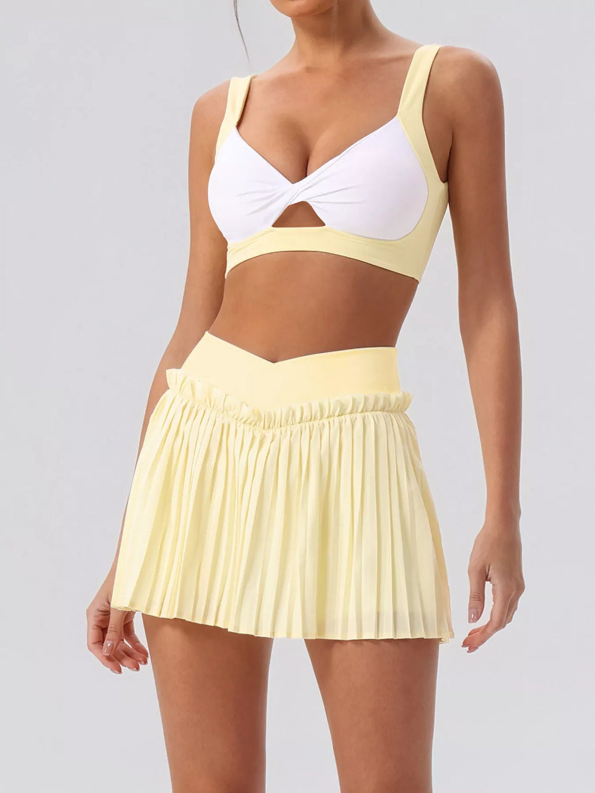 Two-piece set with white V-neck sleeveless top and light-yellow pleated mini skirt