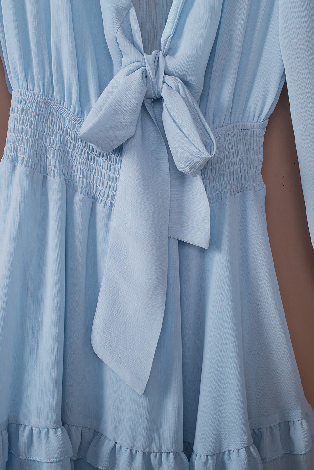 Sky blue flounce dress close-up with large bow tie, smocked waist, and tiered skirt