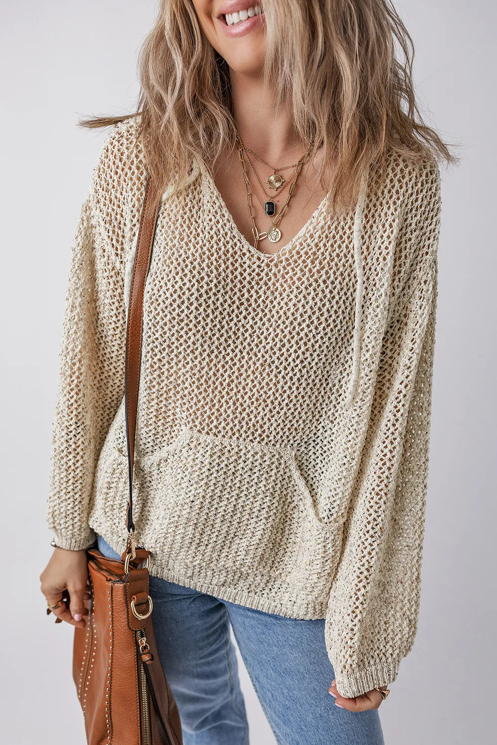 Beige openwork knit hooded top with long sleeves, dropped shoulders, and front pocket