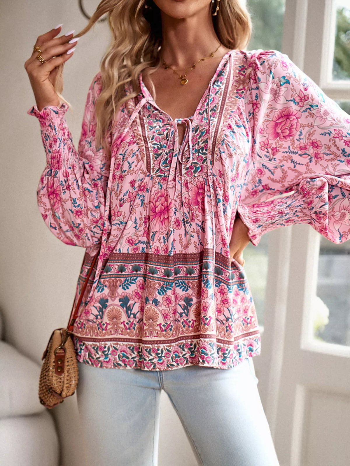 Pink floral tie-neck blouse with loose peasant shape, ruffled neckline, and smocked cuffs