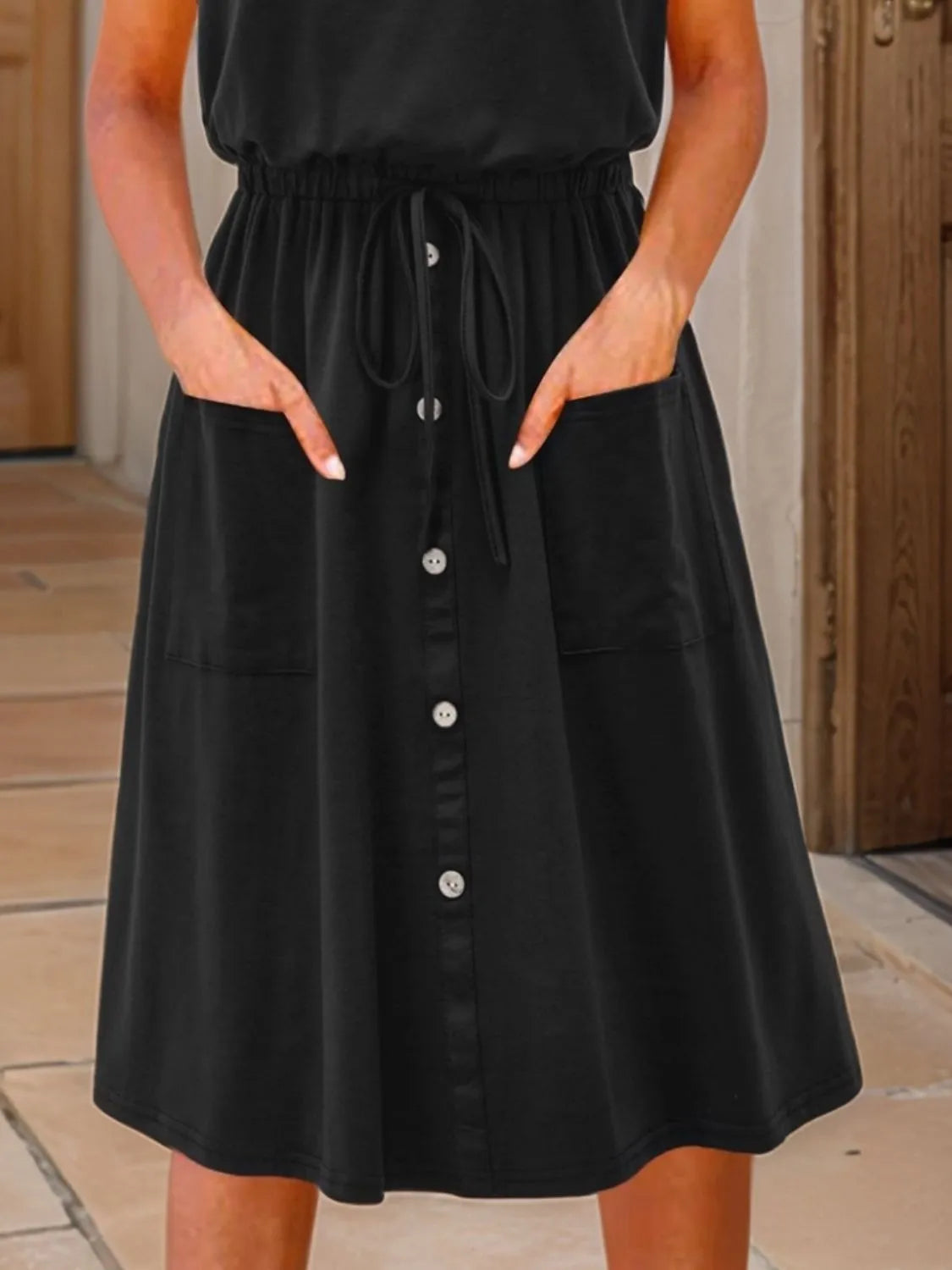 Tank dress, plus-size black sleeveless round-neck with drawstring waist, front button placket, pockets.