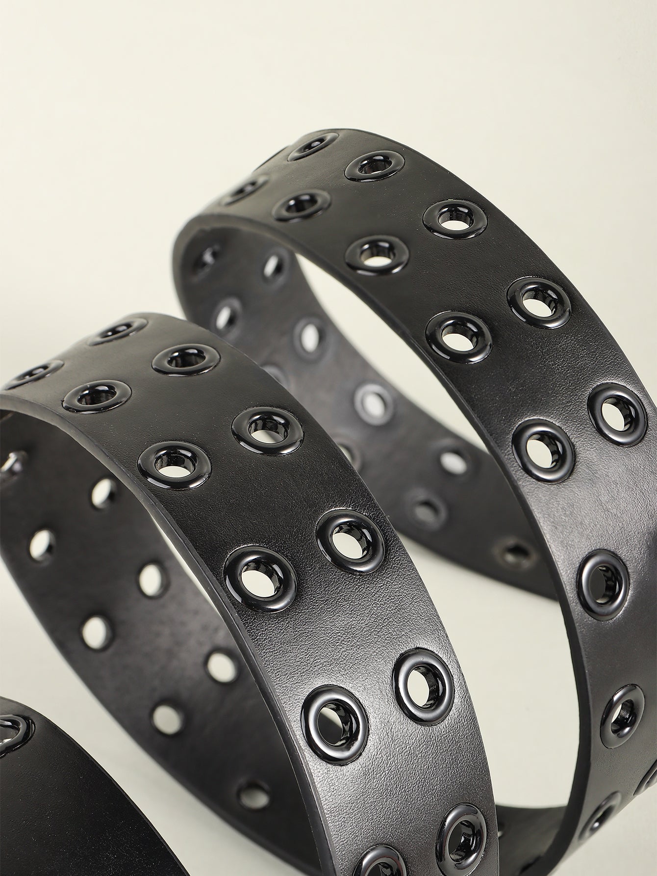 Pair of black vegan leather grommet belts with silver-toned eyelets