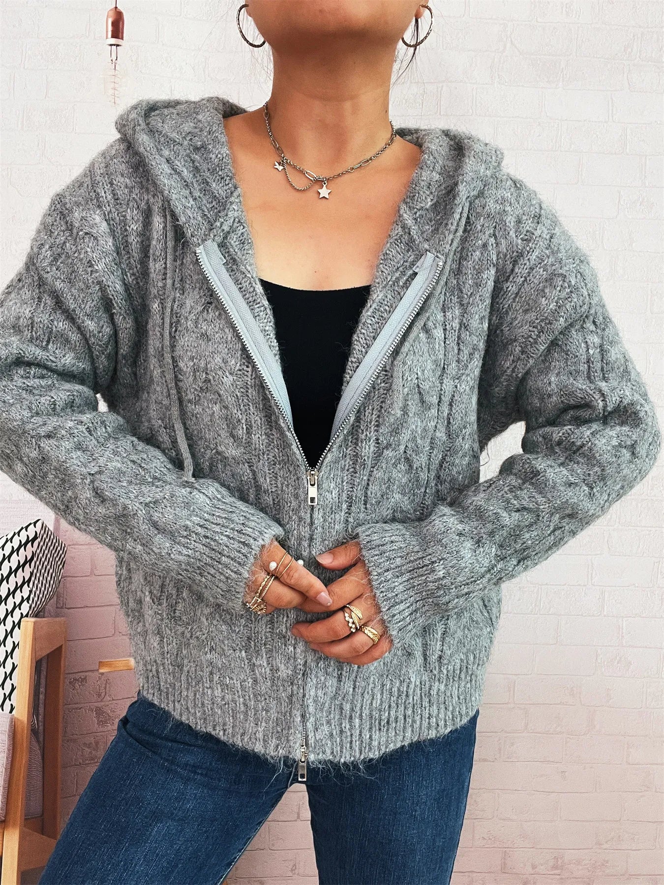 Gray hooded cable knit zip-up cardigan featuring front zipper, long sleeves, ribbed trim.